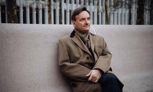 Stephen Hough sitting on a concrete bench