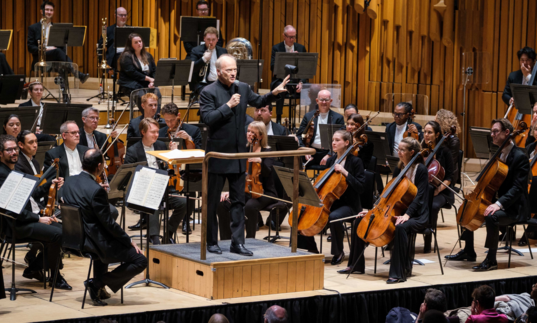 Conductor Gianandrea Noseda holds a microphone and presents his pre-concert Half Six Fix talk