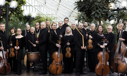 The Academy of Ancient music posing with their instruments in the Barbican Conservatory
