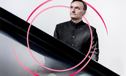 A photo of Stephen Hough with pink circular swirls around him