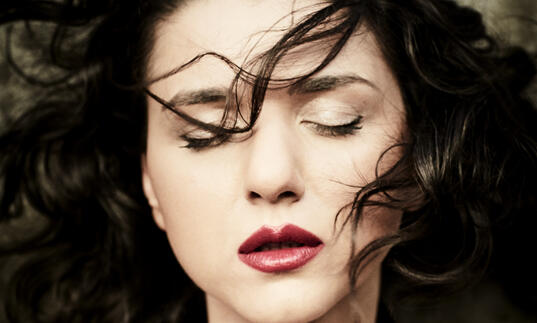 Close up shot of Khatia Buniatishvili with her eyes closed and her hair blowing in her face