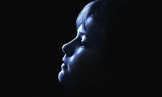 Image of young boy looking up with face in shadow