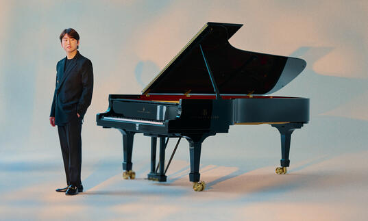 Seong-Jin Cho standing next to a piano