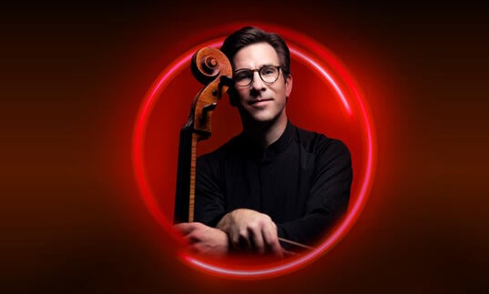 An image of Guy Johnston surrounded by a red circle against a red backdrop