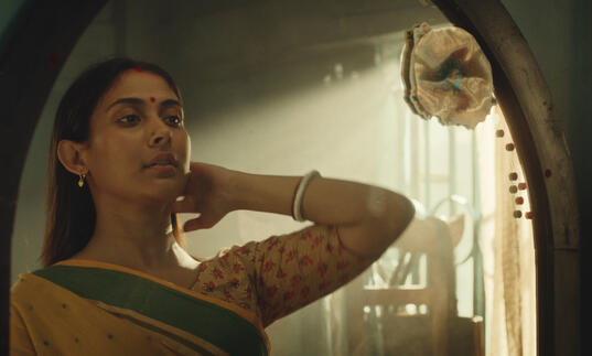 Maloti stares into a mirror, bathed in soft light