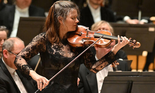 Janine Jansen on the Barbican stage, in front of the orchestra, playing the violin