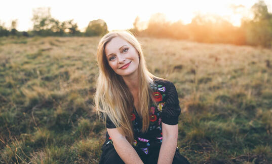 Soprano Lucy Crowe pictured in a field, with the sun setting in the background