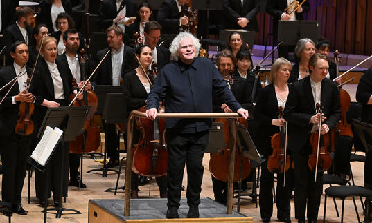 Sir Simon Rattle facing the audience in the Barbican concert hall