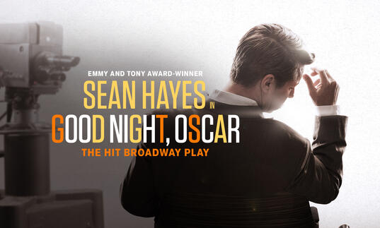 Sean Hayes stands with his back to camera in a suit. The words 'Sean Hayes, Good Night, Oscar' are written in orange and white text over the top'. 