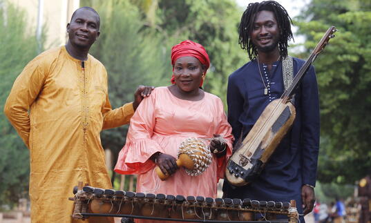 Trio Da Kali posing with their instruments with trees in the background