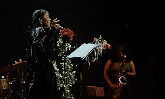 aja monet singing in front of a jazz band