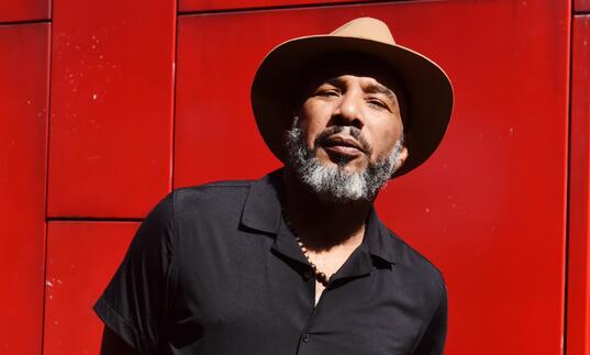 Image of Anthony Joseph in a hat against a red background