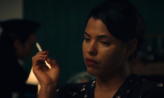 A woman sadly smokes a cigarette
