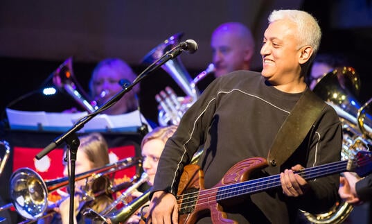 Shri Sriram playing a string instrument in front of a classical brass band