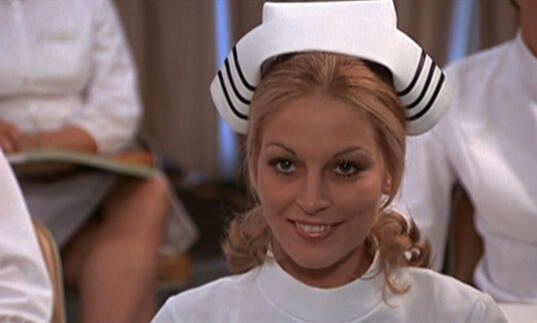 A nurse looks straight ahead, smiling. 