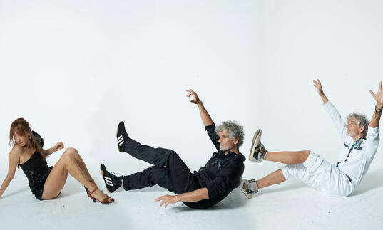 Kazu Makino and twin brothers Simone and Amedeo Pace are swept by an imaginary wind against a white background 