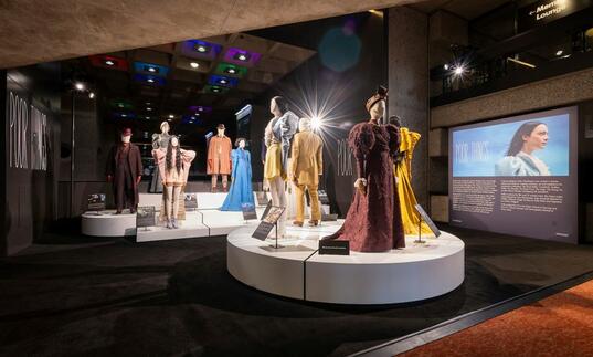 A photo of several costumes displayed on plinths, worn originally by the cast of the film Poor Things