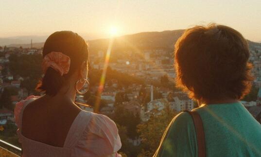 Two women facing a sunlit valley
