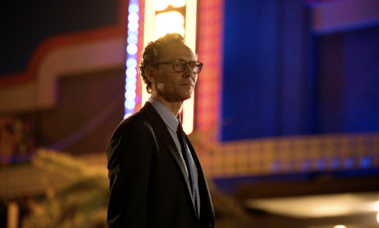 Tom Hiddleston stands in front of a vintage cinema