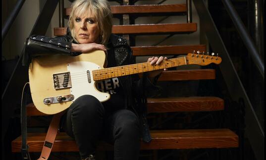 Photo on Lucinda Williams sitting on the steps with guitar