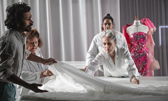 Four people gather around a large piece of white fabric.