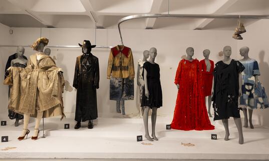 A woman looks at a collection of outfits by a range of designers.