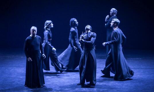 Performers dressed in black gowns on stage. 
