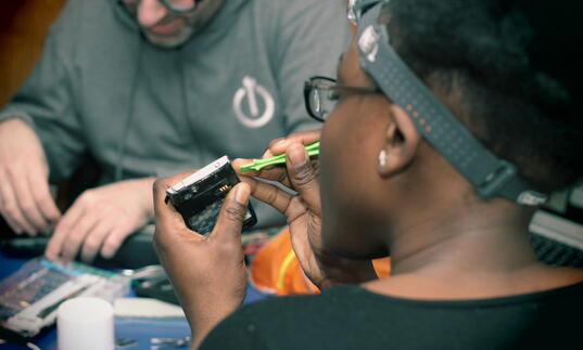 A repairer fixing a small device across from another volunteer with Restart London.