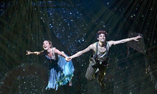 Wendy and Peter holding hands, flying 