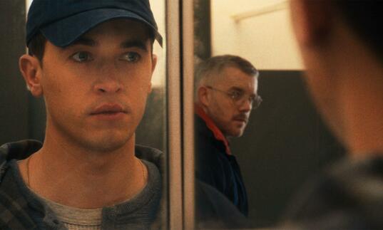 Two man looking at each other through a mirror