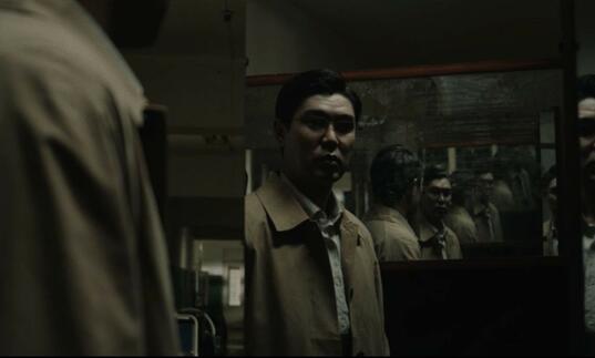 A man stands in an ominous room with mirrors. 