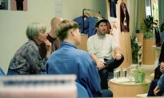 A group of people sit in a room and talk.