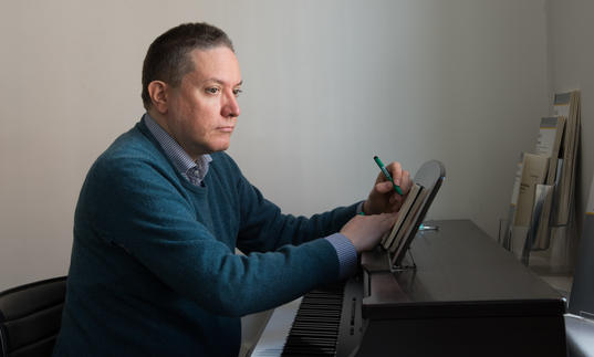 A picture of Julian Anderson writing at the piano