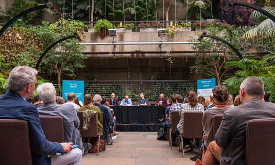 An audience watching a talk in the Barbican Conservatory