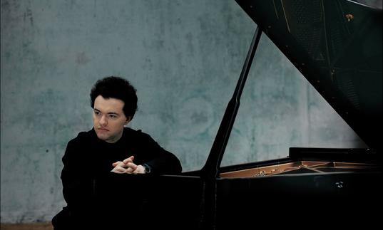 A colour photograph of Evgeny Kissin by a piano