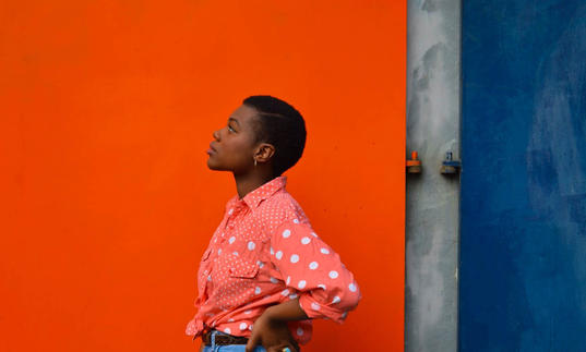 Young woman standing in front of a red wall