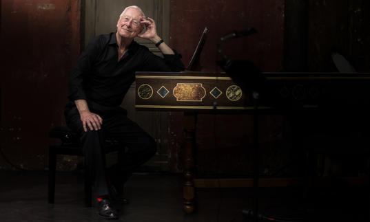 Image of conductor William Christie by a harpsichord