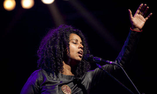 Susheela Raman singing and raising her hand to the sky