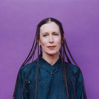 Photo of Meredith Monk in front of a bright purple backdrop