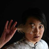 Photo of Theresa Wong holding a feather in front of her face